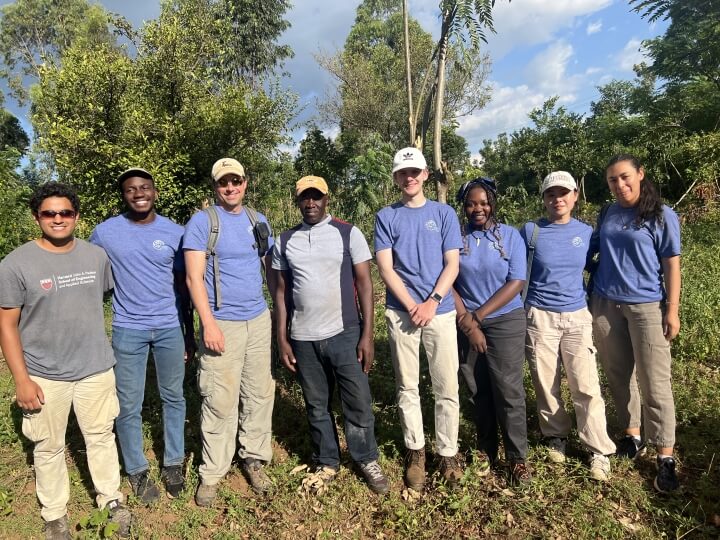 Eight people standing with trees in the background