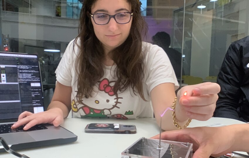 A female Harvard student draws electric current from a minitiarized tesla coil