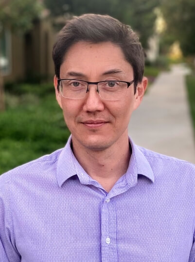 Head shot of Harvard SEAS alumni Chris Wagner wearing a purple shirt and glasses