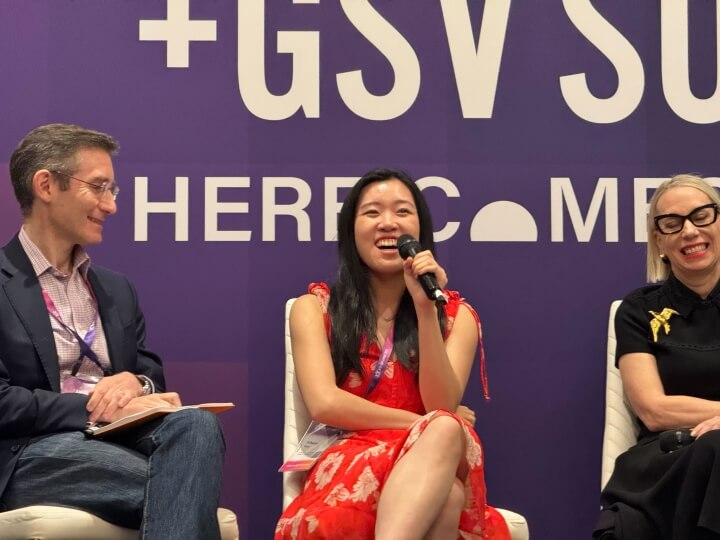 Harvard SEAS Athena Kan, A.B. '19, sitting in a chair and holding a microphone