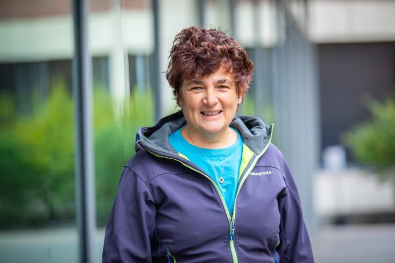 image of smiling person outside with a dark jacket and light blue shirt