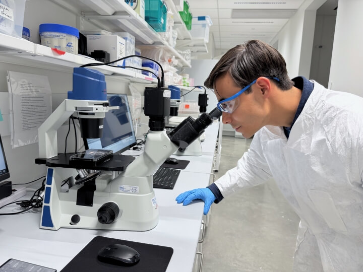 Harvard SEAS student Kieran McDaniel looking through a microscope