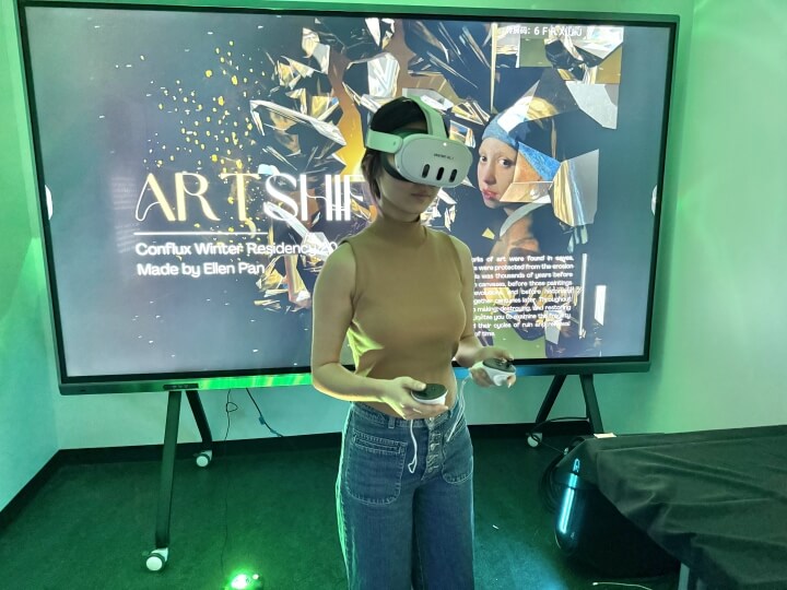 A female Harvard student wearing a virtual reality headset in front of a large screen