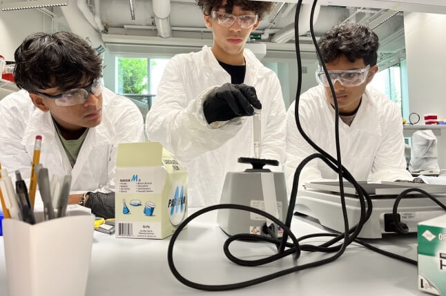 High school students Dominic Jorge, Oishik Chakraborty, and Kabir Gokarn working at a lab table